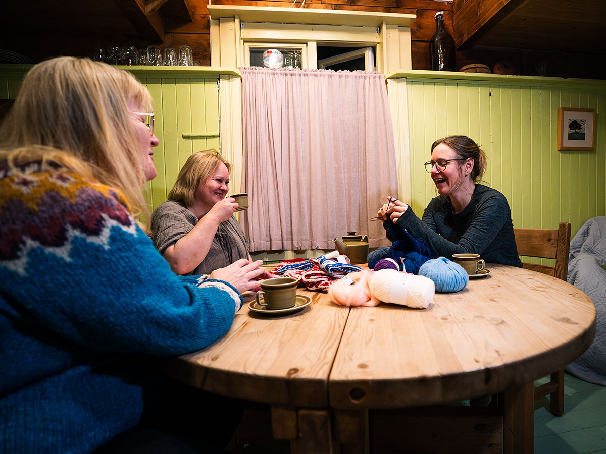 Women knitting together over tea in a cultural workshop setting at Havly Lofoten Retreat.