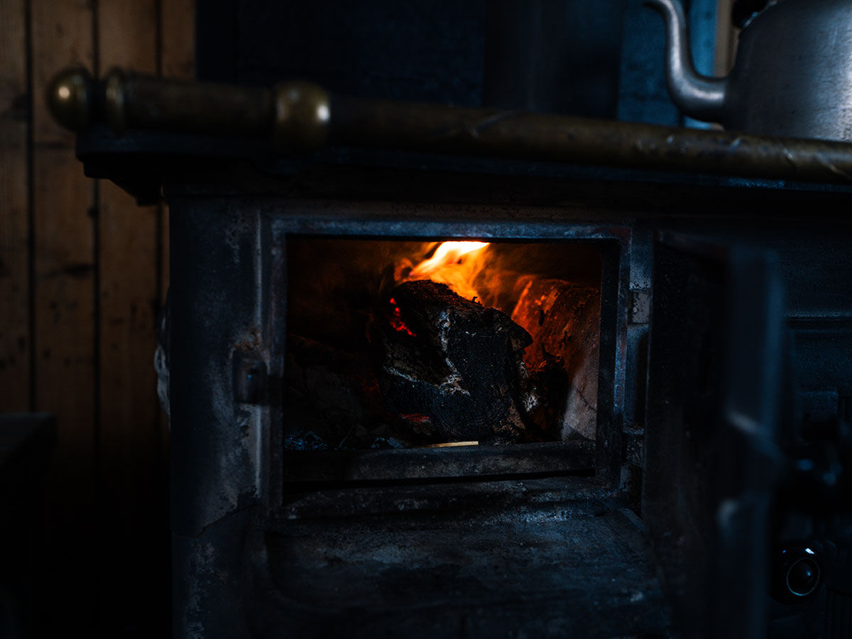 Crackling wood stove fire creating a cozy atmosphere at Havly Lofoten Retreat.