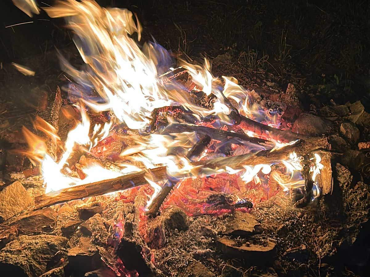Crackling campfire with glowing embers during a calm evening.